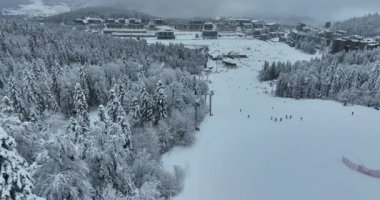 Many skiers and snowboarders skiing down on snowy mountainsides slopes in mountains at ski resort in winter. Family and friends have fun on fresh snow sliding. Bjelasnica mountain. Quality 4k video