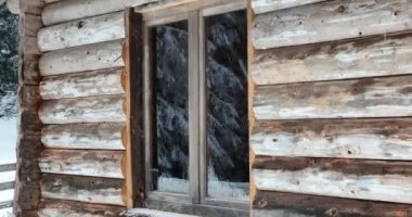 Splendid mountain winter landscape with secluded small wooden alpine cottage among the fir trees fully covered by snow during snow fall. Hi quality 4K slow motion footage. 