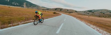 Full length portrait of an active triathlete in sportswear and with a protective helmet riding a bicycle. Selective focus.
