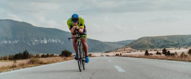 Full length portrait of an active triathlete in sportswear and with a protective helmet riding a bicycle. Selective focus.