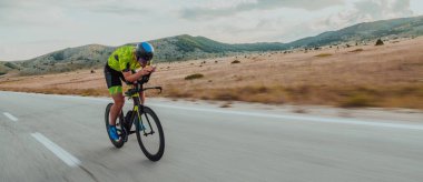 Full length portrait of an active triathlete in sportswear and with a protective helmet riding a bicycle. Selective focus.