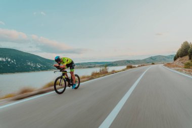 Full length portrait of an active triathlete in sportswear and with a protective helmet riding a bicycle. Selective focus.