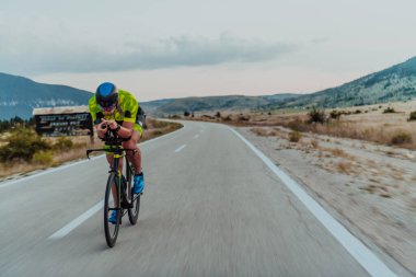Full length portrait of an active triathlete in sportswear and with a protective helmet riding a bicycle. Selective focus.