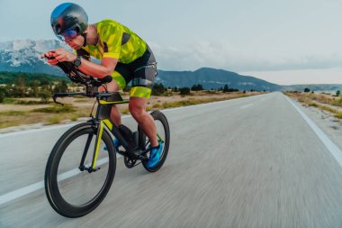 Full length portrait of an active triathlete in sportswear and with a protective helmet riding a bicycle. Selective focus.