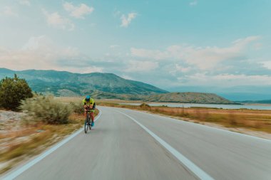 Full length portrait of an active triathlete in sportswear and with a protective helmet riding a bicycle. Selective focus.
