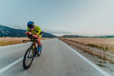 Full length portrait of an active triathlete in sportswear and with a protective helmet riding a bicycle. Selective focus.