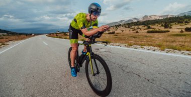 Full length portrait of an active triathlete in sportswear and with a protective helmet riding a bicycle. Selective focus.
