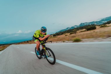 Full length portrait of an active triathlete in sportswear and with a protective helmet riding a bicycle. Selective focus.