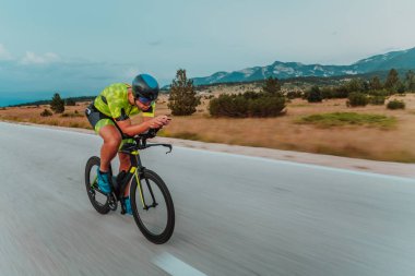 Full length portrait of an active triathlete in sportswear and with a protective helmet riding a bicycle. Selective focus.