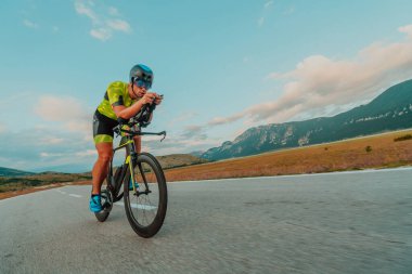 Full length portrait of an active triathlete in sportswear and with a protective helmet riding a bicycle. Selective focus.