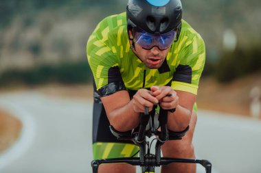 Close up photo of an active triathlete in sportswear and with a protective helmet riding a bicycle. Selective focus. 