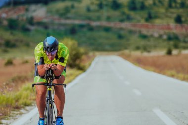 Full length portrait of an active triathlete in sportswear and with a protective helmet riding a bicycle. Selective focus.
