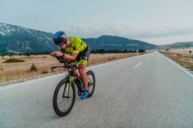 Full length portrait of an active triathlete in sportswear and with a protective helmet riding a bicycle. Selective focus.