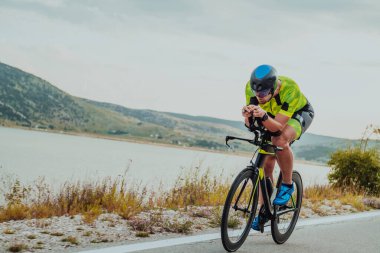 Full length portrait of an active triathlete in sportswear and with a protective helmet riding a bicycle. Selective focus.