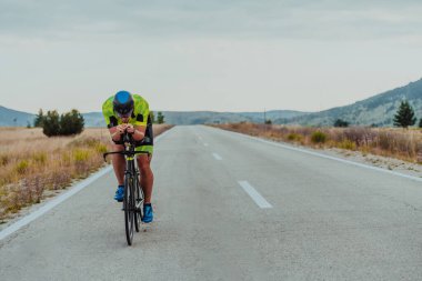 Full length portrait of an active triathlete in sportswear and with a protective helmet riding a bicycle. Selective focus.