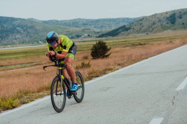 Full length portrait of an active triathlete in sportswear and with a protective helmet riding a bicycle. Selective focus.