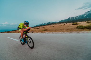 Full length portrait of an active triathlete in sportswear and with a protective helmet riding a bicycle. Selective focus.