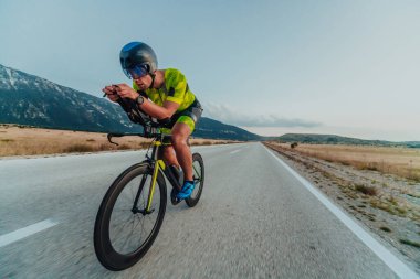 Full length portrait of an active triathlete in sportswear and with a protective helmet riding a bicycle. Selective focus.