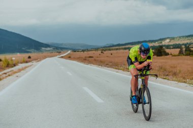 Full length portrait of an active triathlete in sportswear and with a protective helmet riding a bicycle. Selective focus.