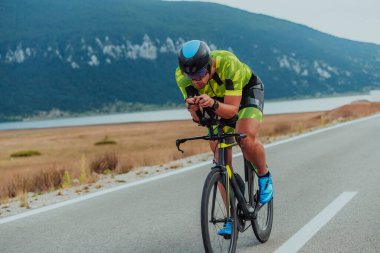 Full length portrait of an active triathlete in sportswear and with a protective helmet riding a bicycle. Selective focus.