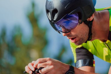 Close up photo of an active triathlete in sportswear and with a protective helmet riding a bicycle. Selective focus. 
