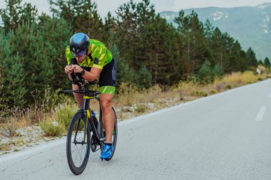 Full length portrait of an active triathlete in sportswear and with a protective helmet riding a bicycle. Selective focus.