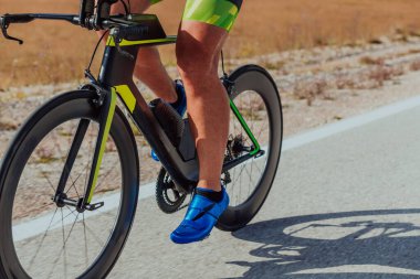 Full length portrait of an active triathlete in sportswear and with a protective helmet riding a bicycle. Selective focus.
