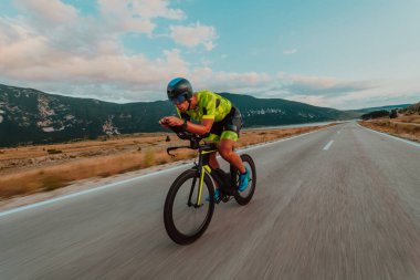 Full length portrait of an active triathlete in sportswear and with a protective helmet riding a bicycle. Selective focus.