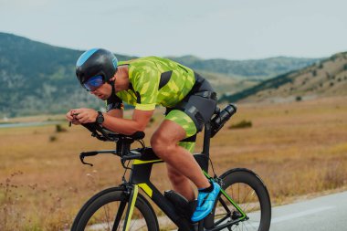 Full length portrait of an active triathlete in sportswear and with a protective helmet riding a bicycle. Selective focus.