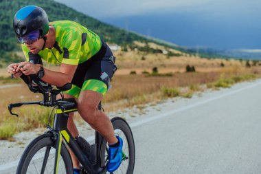 Full length portrait of an active triathlete in sportswear and with a protective helmet riding a bicycle. Selective focus.