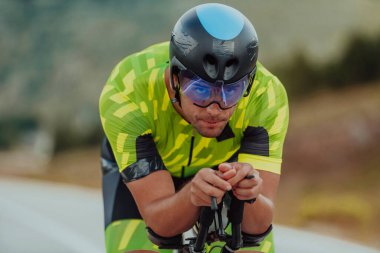 Full length portrait of an active triathlete in sportswear and with a protective helmet riding a bicycle. Selective focus.