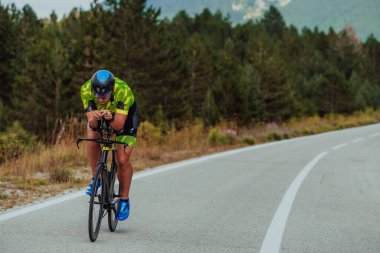 Full length portrait of an active triathlete in sportswear and with a protective helmet riding a bicycle. Selective focus.