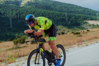Full length portrait of an active triathlete in sportswear and with a protective helmet riding a bicycle. Selective focus.