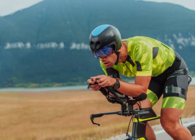 Full length portrait of an active triathlete in sportswear and with a protective helmet riding a bicycle. Selective focus.