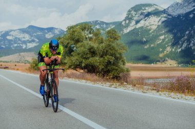 Full length portrait of an active triathlete in sportswear and with a protective helmet riding a bicycle. Selective focus.
