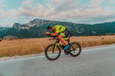 Full length portrait of an active triathlete in sportswear and with a protective helmet riding a bicycle. Selective focus.
