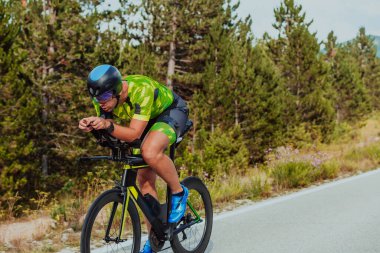 Full length portrait of an active triathlete in sportswear and with a protective helmet riding a bicycle. Selective focus.