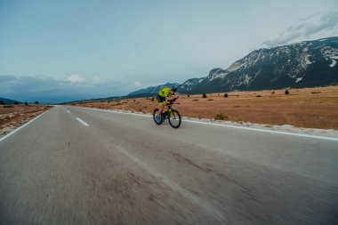 Full length portrait of an active triathlete in sportswear and with a protective helmet riding a bicycle. Selective focus.