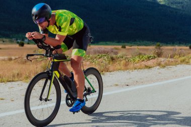 Full length portrait of an active triathlete in sportswear and with a protective helmet riding a bicycle. Selective focus.
