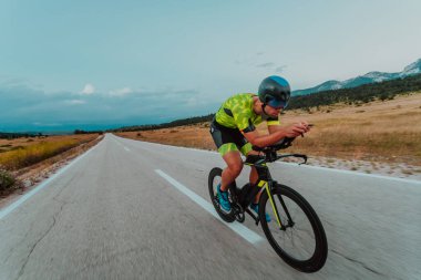 Full length portrait of an active triathlete in sportswear and with a protective helmet riding a bicycle. Selective focus.