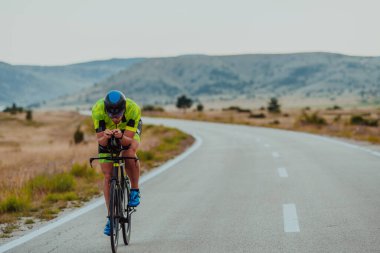 Full length portrait of an active triathlete in sportswear and with a protective helmet riding a bicycle. Selective focus.