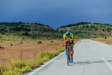Full length portrait of an active triathlete in sportswear and with a protective helmet riding a bicycle. Selective focus.