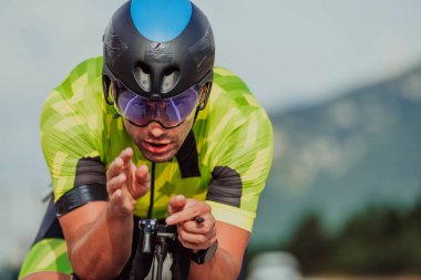 Close up photo of an active triathlete in sportswear and with a protective helmet riding a bicycle. Selective focus. 