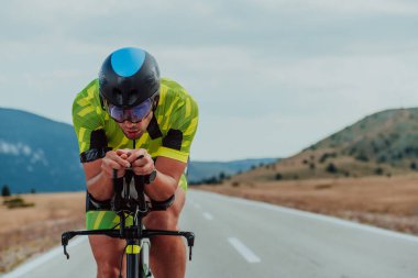 Close up photo of an active triathlete in sportswear and with a protective helmet riding a bicycle. Selective focus. 