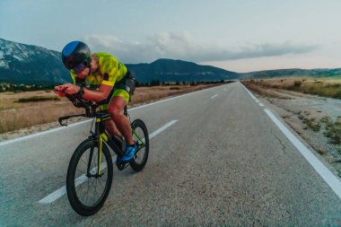 Full length portrait of an active triathlete in sportswear and with a protective helmet riding a bicycle. Selective focus.