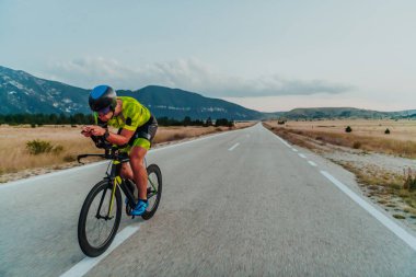 Full length portrait of an active triathlete in sportswear and with a protective helmet riding a bicycle. Selective focus.