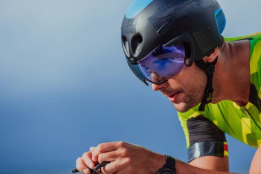 Close up photo of an active triathlete in sportswear and with a protective helmet riding a bicycle. Selective focus. 