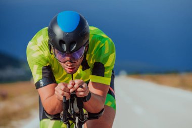 Close up photo of an active triathlete in sportswear and with a protective helmet riding a bicycle. Selective focus. 