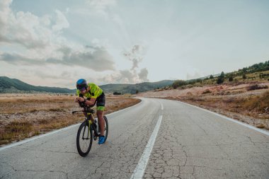 Full length portrait of an active triathlete in sportswear and with a protective helmet riding a bicycle. Selective focus.