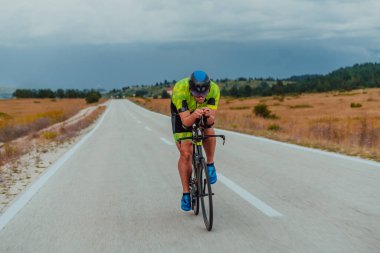 Full length portrait of an active triathlete in sportswear and with a protective helmet riding a bicycle. Selective focus.